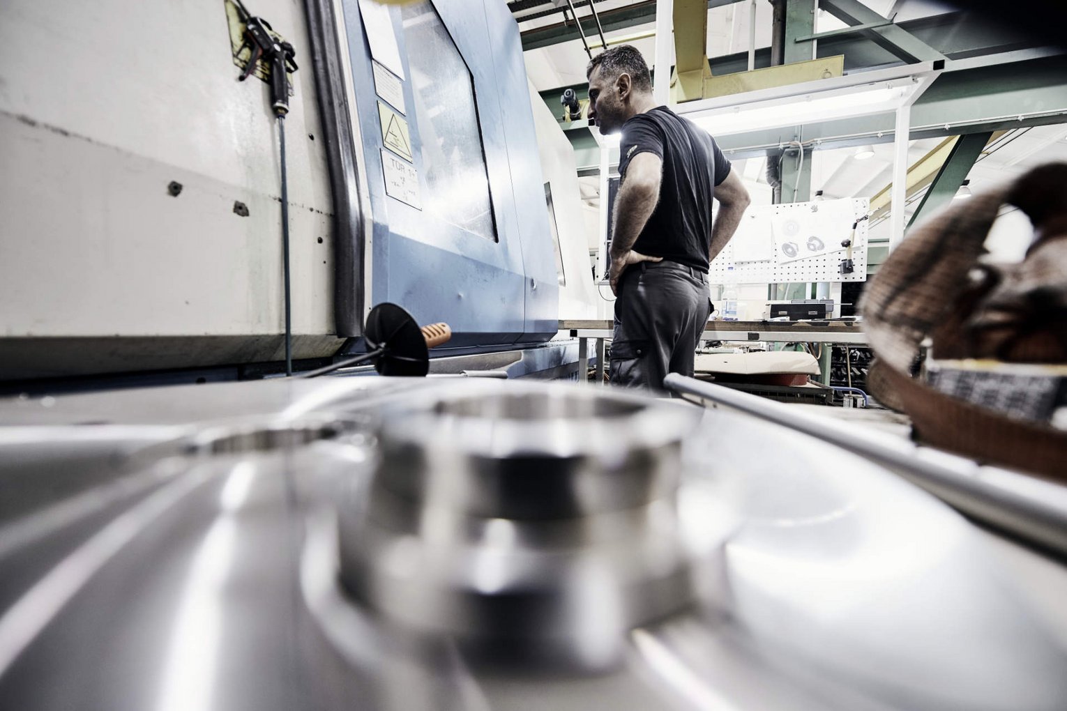 Produktion Schmid Metallbearbeitung Ein Mitarbeiter von Schmid Metallbearbeitung überwacht eine Maschine in der Produktion